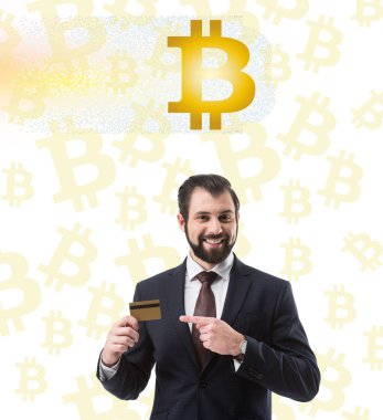 kredi kartı, beyaz bitcoin sembolleri gösteren gülümseyen iş adamı