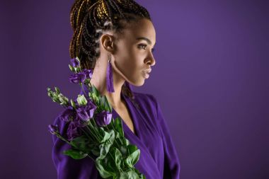Moda Afro-Amerikan kız mor eustoma çiçeklerle poz izole mor, ultra violet eğilim