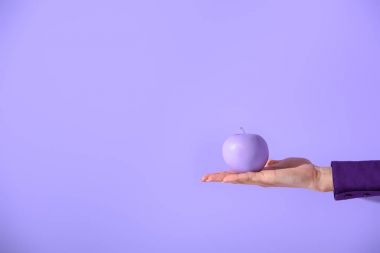 cropped view on female hand holding purple apple, isolated on ultra violet clipart