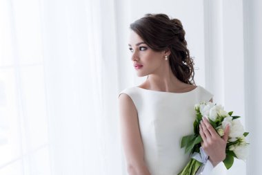 Düğün buketi tutarak ve penceresine bakarak güzel gelin