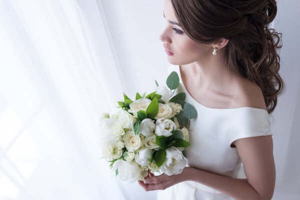 attractive bride in traditional dress holding wedding bouquet