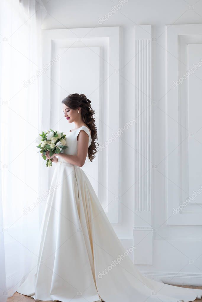 bride posing in elegant white dress with wedding bouquet