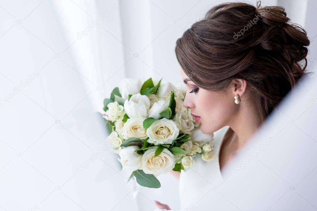 attractive brunette bride sniffing wedding bouquet