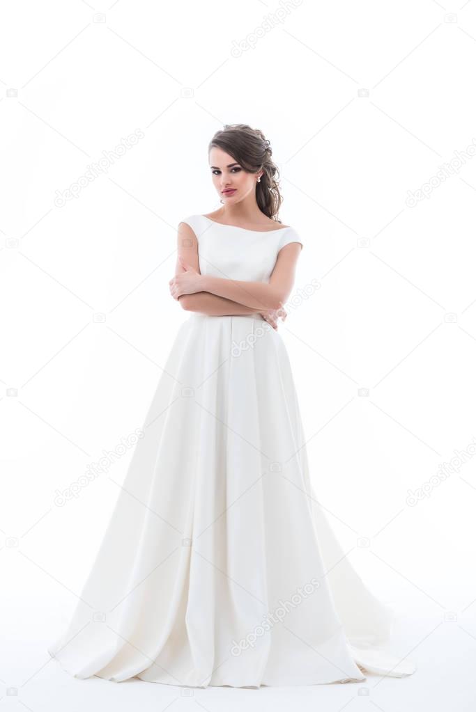 attractive bride posing in traditional wedding dress with crossed arms, isolated on white