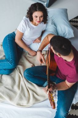 Adamın kız arkadaşı ile akustik gitar çalmaya yüksek açılı görünüş