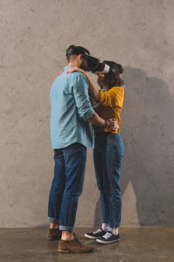 Side view of couple holding each other and using virtual reality headset clipart