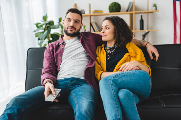 Woman looking at boyfriend while he holding remote controller