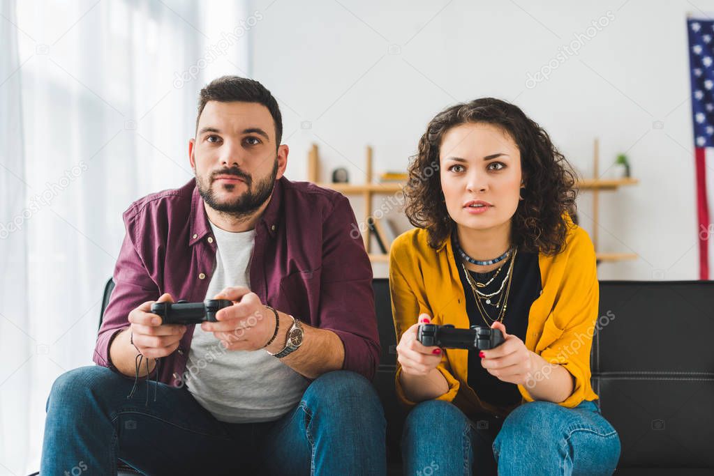 Front view of young couple holding joysticks in hands