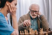 Idősebb ember élvezi sakkozni nővér