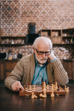 Thoughtful elder man by chess board clipart