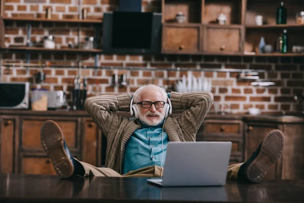 Relaxed Old Man Headphones Using Laptop Feet Table — Stock Photo, Image