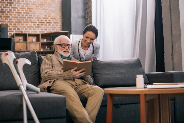 Arzt Blickt Auf Buch Den Händen Eines Älteren Mannes — Stockfoto