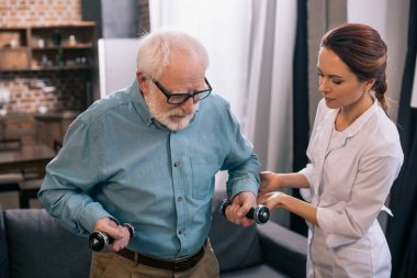 Kadın doktor ve fizyoterapi sırasında dumbbells ile komuta sizde