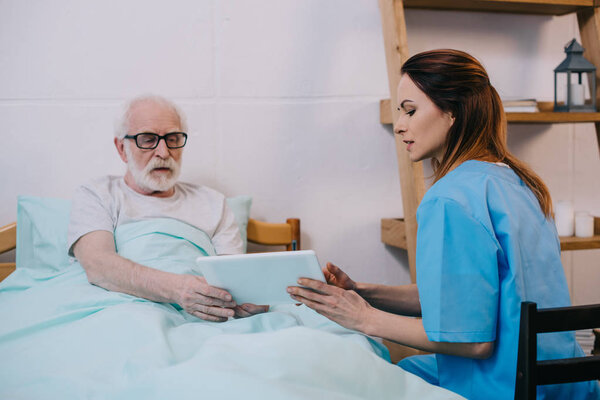 Senior patient and caregiver using tablet