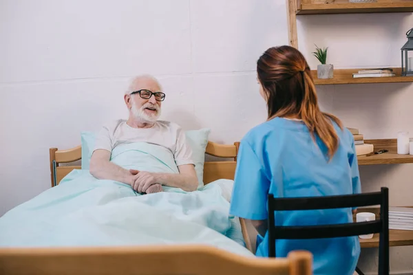 Glimlachend Oude Patiënt Bed Praten Met Verpleegkundige — Stockfoto