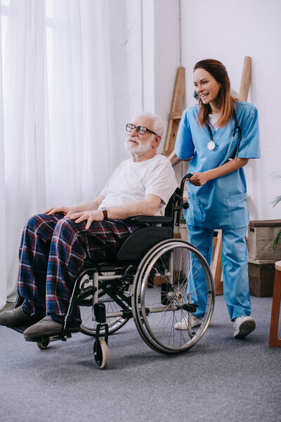 Nurse pushing wheelchair with senior patient