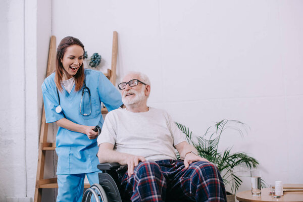 Laughing nurse and senior patient in wheelchair
