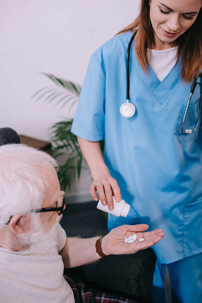 Nurse measuring pills for senior male patient