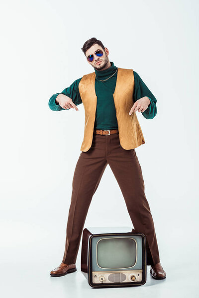 handsome retro styled man pointing on television on white