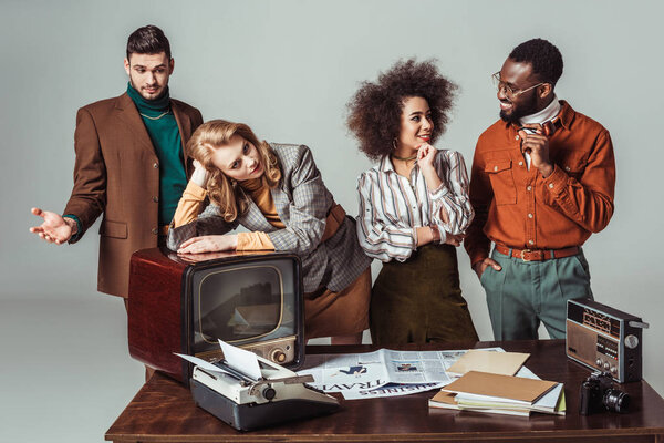happy multicultural retro styled journalists at newsroom isolated on grey