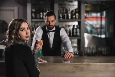 Barmen ve dövmeli kız bar counter kameraya bakarak