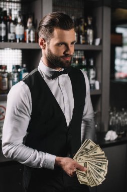 happy handsome bartender holding tips at bar clipart