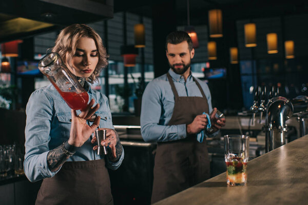 female and male bartenders working at bar