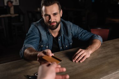 sayaç oturma ve barmene kredi kartı veren ziyaretçi kırpılmış görüntü