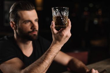man sitting at bar counter and looking at glass of whiskey at bar clipart