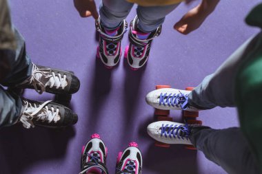 partial view of family in roller skates standing on roller rink clipart