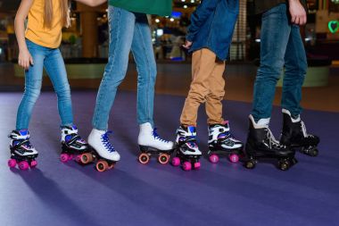 partial view of parents and kids skating on roller rink together clipart