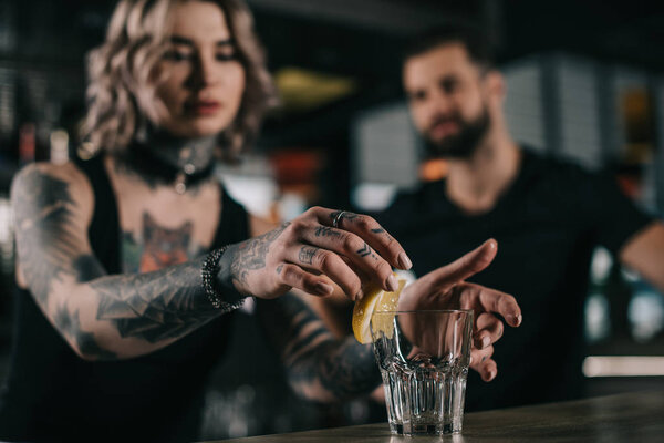 бармен кладет кусок лимона в стекло в баре
