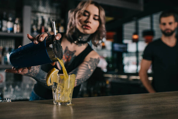 tattooed bartender preparing drink at bar