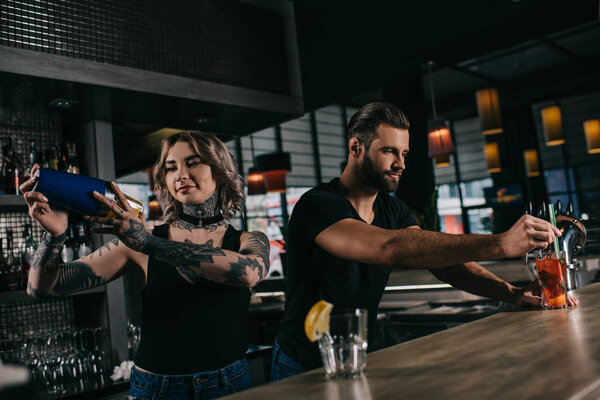 young bartenders preparing alcohol drinks at bar