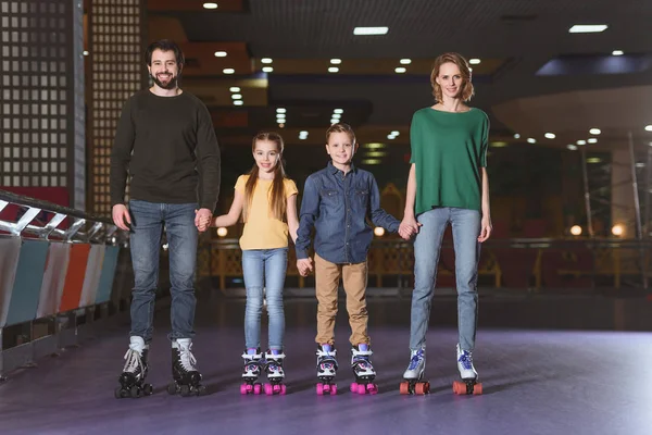 Felice famiglia che si tiene per mano mentre pattina insieme sulla pista di pattinaggio — Foto Stock