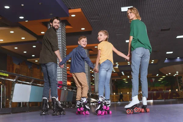 Back view of family holding hands while skating on roller rink together — Stock Photo, Image