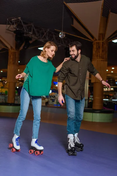 Young couple skating together on roller rink — Stock Photo, Image