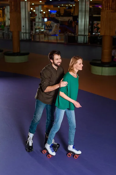 Young smiling couple skating together on roller rink — Stock Photo, Image