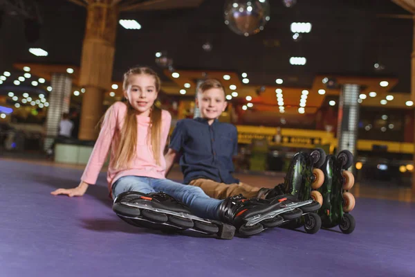 Selectieve aandacht van schattige broers en zussen in rolschaatsen rust na het schaatsen op de ijsbaan roller — Gratis stockfoto