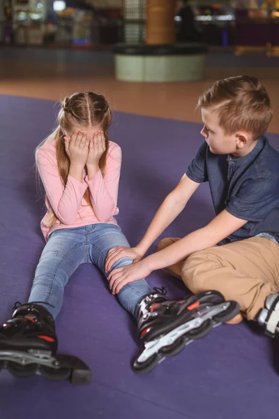 Brother cheering up crying sister in roller skates on roller rink — Stock Photo, Image