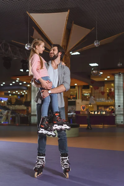 Happy father holding daughter in roller skates on roller rink — Stock Photo, Image