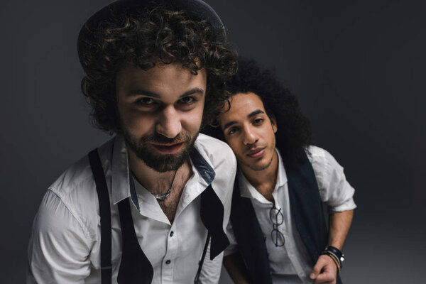 close-up shot of happy stylish men looking at camera on black