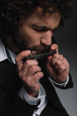 close-up portrait of expressive young man playing harmonica on black clipart
