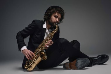 Sakallı jazzman katta otururken saksafon oynamaya