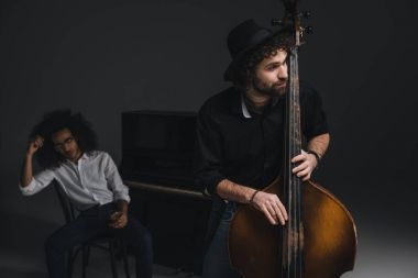 Viyolonsel depresif ortağı arka plan üzerinde bulanık Piano oturan süre oynayan adam