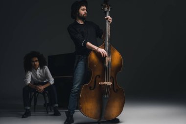 Viyolonsel ortağı arka plan üzerinde bulanık Piano oturan süre oynayan yakışıklı genç