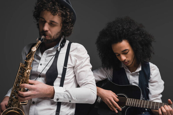 duet of musicians playing sax and guitar on black