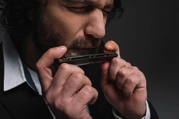 Close-up portrait of expressive musician playing harmonica on black — Stock Photo, Image