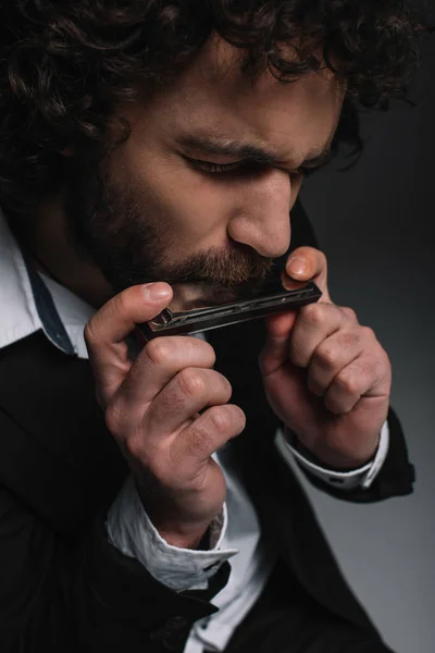 Retrato de cerca del joven expresivo tocando la armónica en negro — Foto de Stock