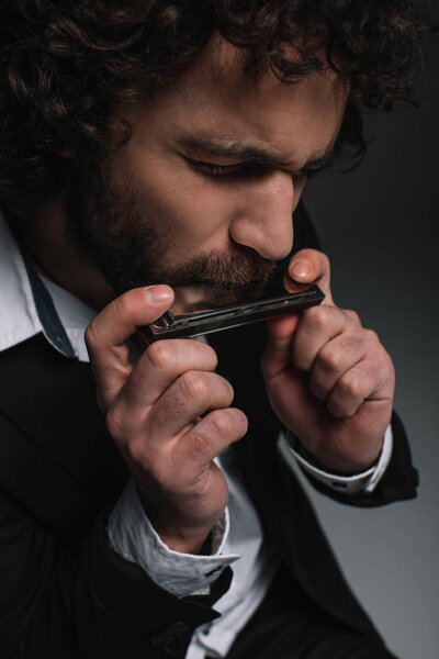 close-up portrait of expressive young man playing harmonica on black